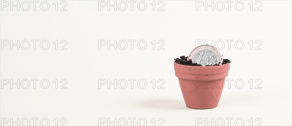One Euro coin in small flowerpot, money growing, financial planning, profitable investment, hope