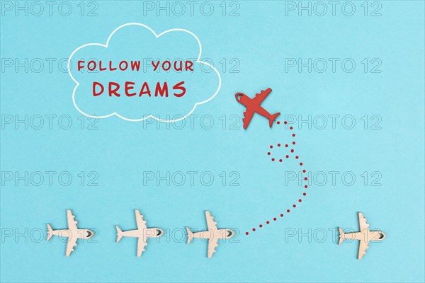 Red airplanes takes a different direction, flying to the cloud with the phrase follow your dreams,