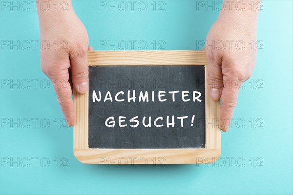 Holding a chalkboard in the hands, looking for a new tenant is standing in german language on the