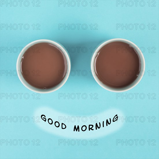 Cup of coffee building the eyes of the funny face, mouth with the phrase good morning, wake up in