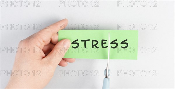 The word stress is standing on a paper, cutting the word with scissors, burnout concept, work life