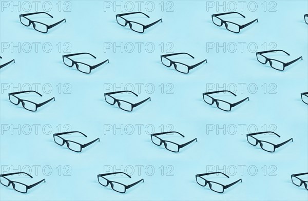 Many eyeglasses with a black frame on a blue background, copy space for text