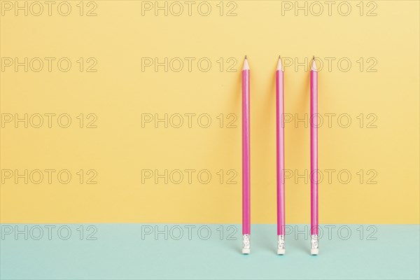 Pink pencils on a yellow and blue background, minimalism, creative, surreal and education concept,