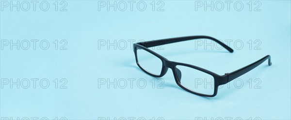 Glasses with a black frame on a blue background, copy space for text