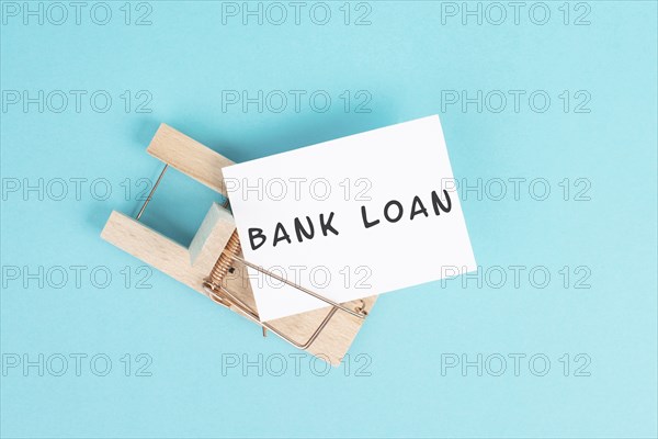 Paper with the words bank loan in a mousetrap, finanicial debt, inflation, risky credit and