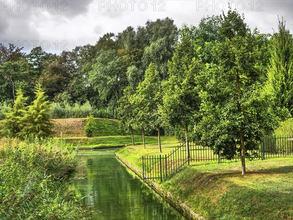 Green parkland with canal, fenced by trees, reflecting water and green meadow, groenlo, gelderland,