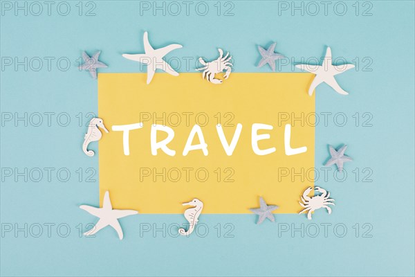The word travel is standing on a yellow colored paper, sea stars, seahorses and crab bulding a