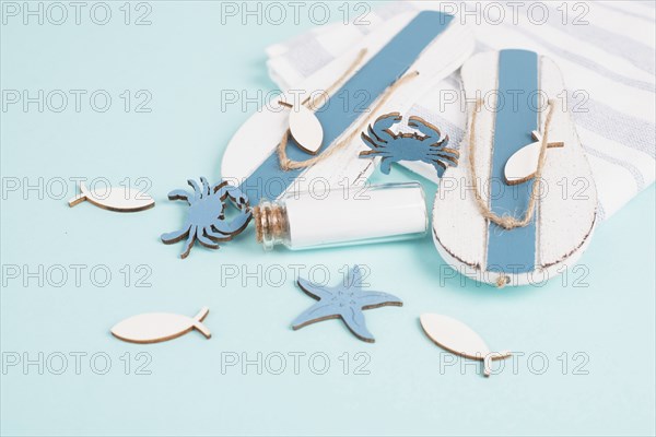 Blue colored summer and holiday background, flip flops, sea stars and a glass bootle with copy