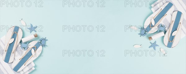 Blue colored summer and holiday background, flip flops, sea stars and a glass bootle with copy