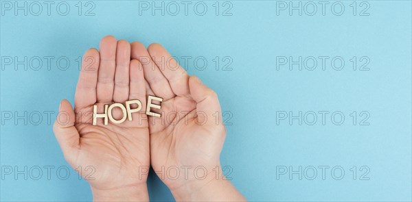 Holding the word hope in the palm of the hands, trust and believe concept, having faith in the