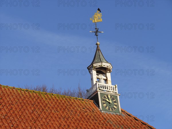 Church tower with clock and golden weather vane under a clear sky, greetsiel, east frisia, germany