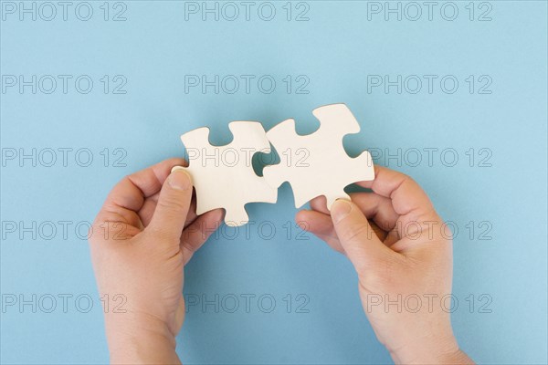 Holding two pieces of a puzzle in the hands, connecting together as a team, solving a problem,