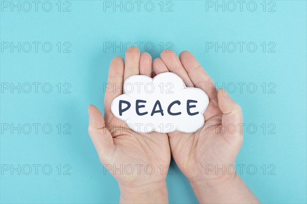 Holding a cloud with the word peace in the hands, stop war, support, living peaceful together