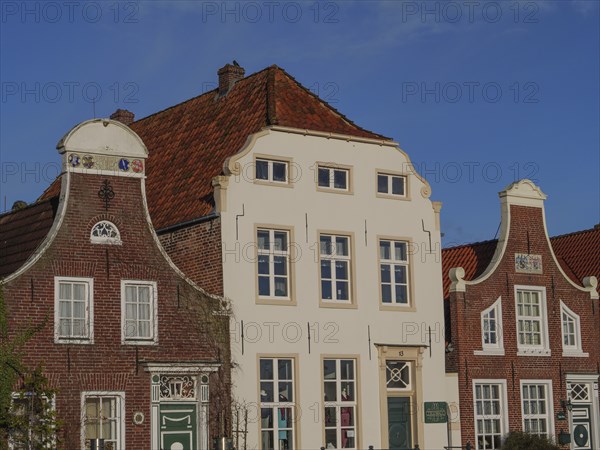 Three historic houses with ornate facades and gables under a clear sky, greetsiel, east frisia,