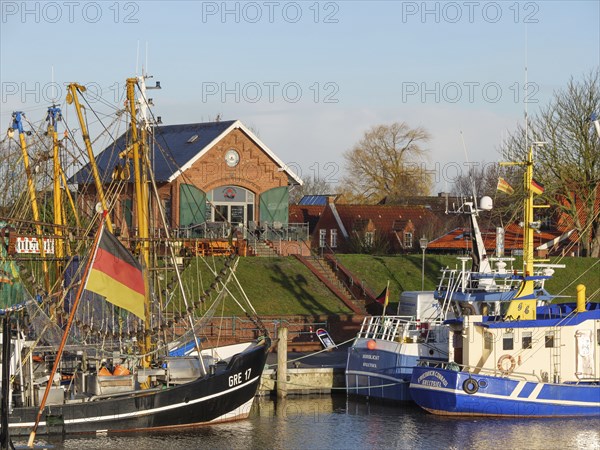 Fishing boats and colourful flags in the harbour, behind reddish houses under a clear sky,