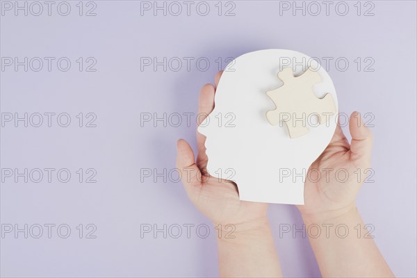 Holding a head with a puzzle piece, mental disease like Autism, Alzheimer, stroke awareness,