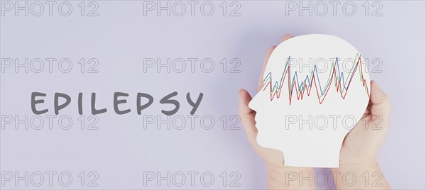 Holding a head in the hands, epilepsy disorder awareness, brain waves, mental health care, paper