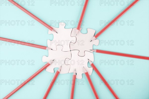 Working as a team, puzzle pieces connect together, pencils point to the jigsaw, brainstorming for