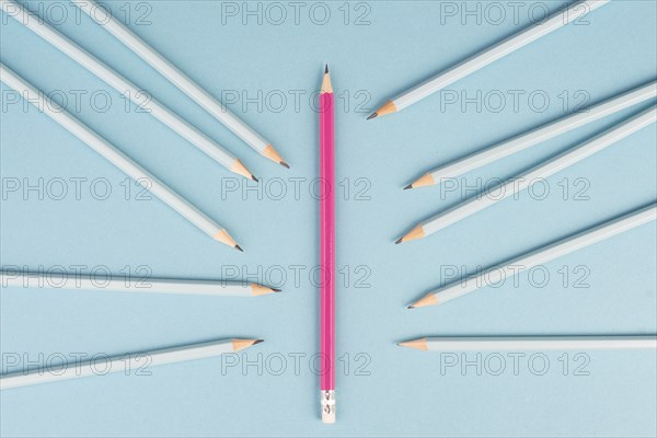 Blue pencils point to the pink one, standing out from the crowd concept, be different, leadership,
