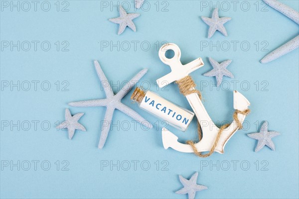 Blue colored summer and holiday background, anchor, sea stars and a glass bootle with the word