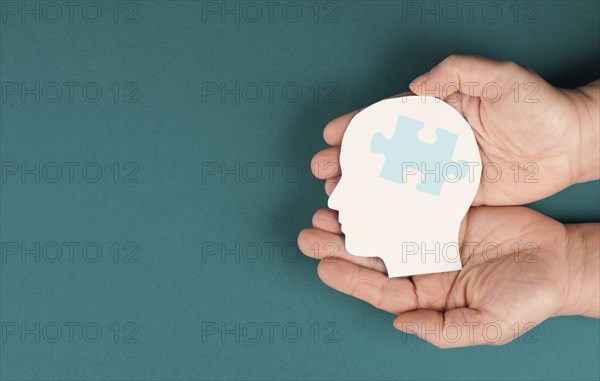 Holding a head with a puzzle piece, mental disease like Autism, Alzheimer, stroke awareness,