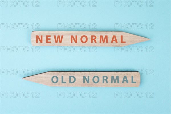 The words new and old normal are standing on wooden arrows, transformation of society after