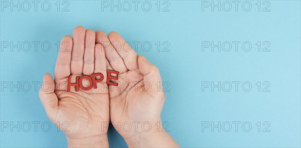 Holding the word hope in the palm of the hands, trust and believe concept, having faith in the