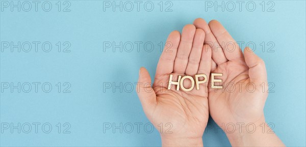 Holding the word hope in the palm of the hands, trust and believe concept, having faith in the