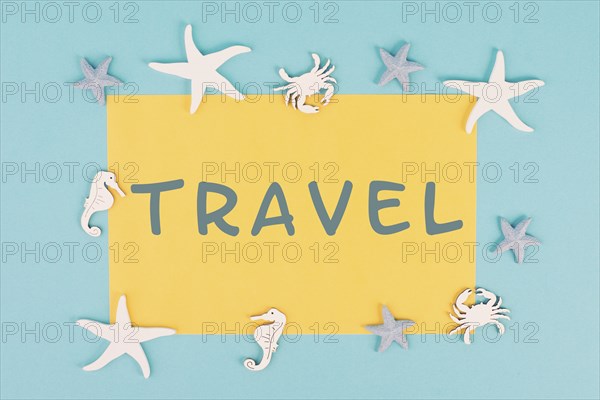 The word travel is standing on a yellow colored paper, sea stars, seahorses and crab bulding a
