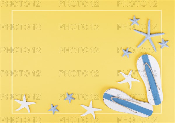 Yellow colored summer and vacation background, slippers and sea stars building a frame, copy space