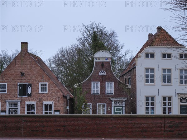 Three historic house fronts with brick facades in front of a cloudy sky, greetsiel, east frisia,