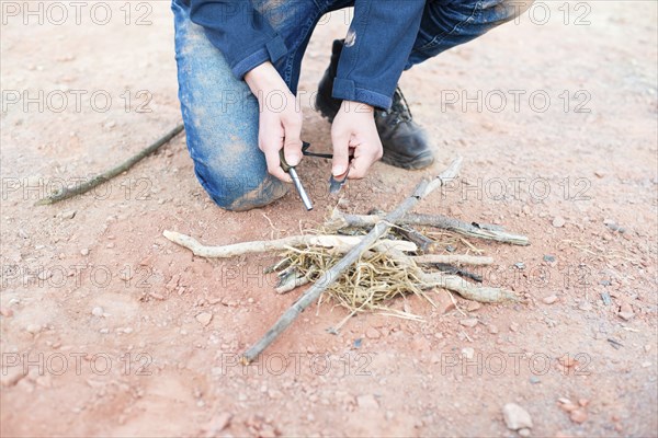 Starting a fire with a firesteel, survival and adventure equipment, outdoor skill, man making a