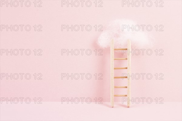 Ladder with a cloud on top, pink rose colored background, copy space, dreaming of success, creative