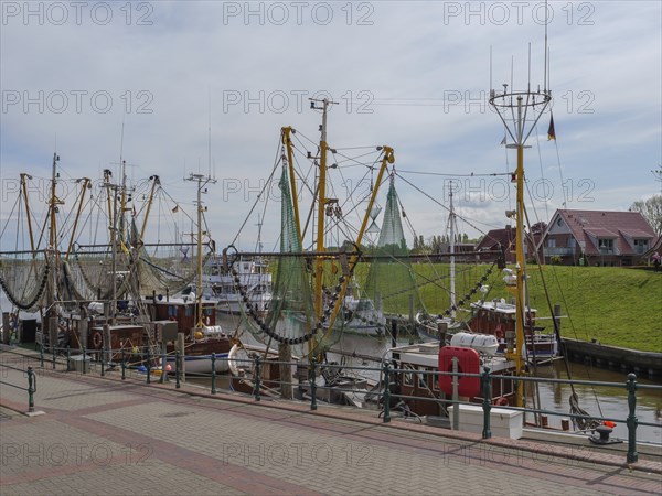 Several fishing boats with stretched nets in the quiet harbour at the pier under a cloudy sky,