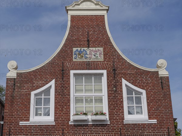 A facade of a historic building with red brick walls and white window frames, Greetsiel, East