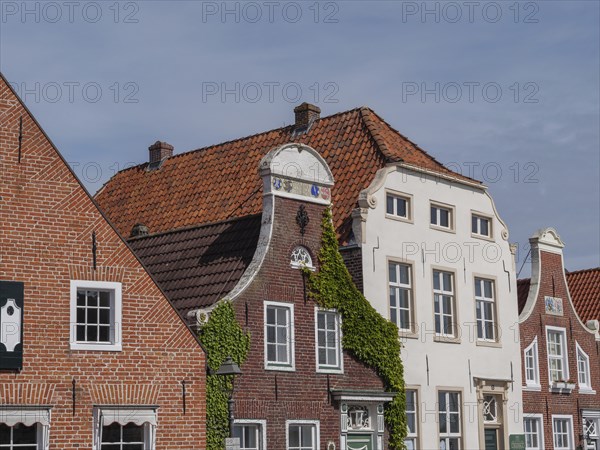Historic houses with brick facades and tiled roofs, some overgrown with climbing plants, greetsiel,