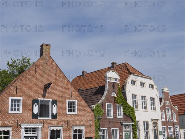 Historic brick houses with gabled roofs and plastered facades under a clear sky, greetsiel, east