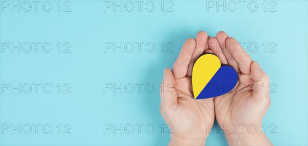 Holding a heart with the flag of Ukraine, national idendity, war crisis between Ukraine and Russia,