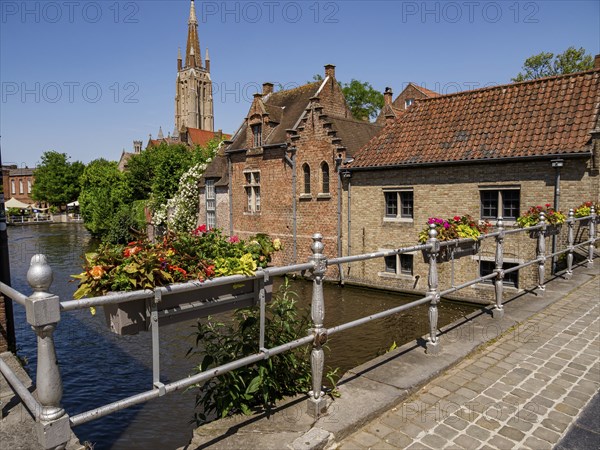 Picturesque bridge with flowers, historic buildings and church tower, sunny summer atmosphere by