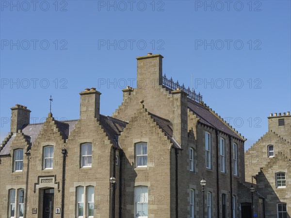 Historic brick buildings with chimneys and windows, shot under a clear blue sky, lerwick,