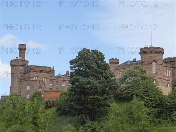 A large castle on a green hill, surrounded by trees and under a blue sky, inverness, scotland,