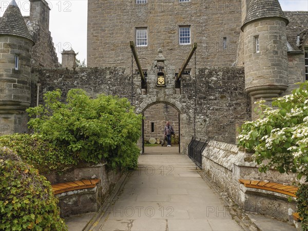 A historic entrance with Tor tor to a castle, flanked by stone walls and benches, inverness,