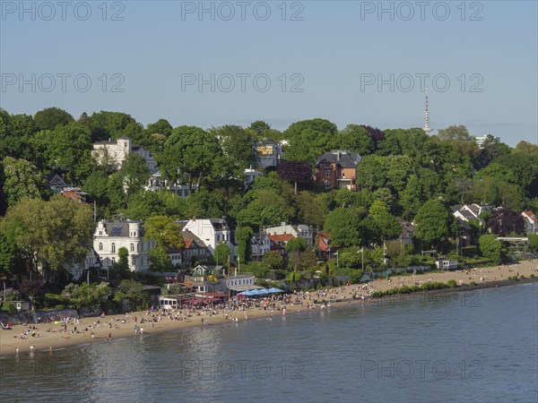 Spacious beach by the water with trees and buildings in the background, relaxed atmosphere, Elbe,
