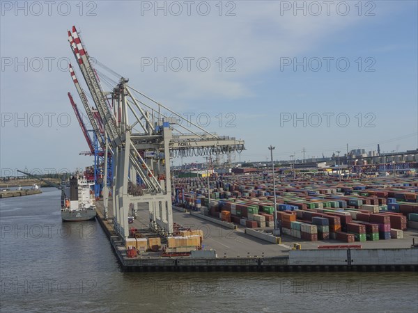 Large cranes in the harbour loading containers, cargo ship at the quay, many containers stacked,