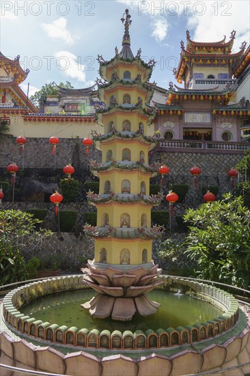 A pagoda in the centre of a water fountain in a temple complex with red lanterns, Pattaya,