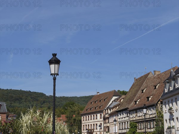 Street lamp in front of a row of traditional houses with green hills in the background,