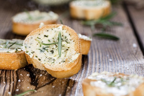 Baguette with Herb Butter and Rosemary on rustic wooden background