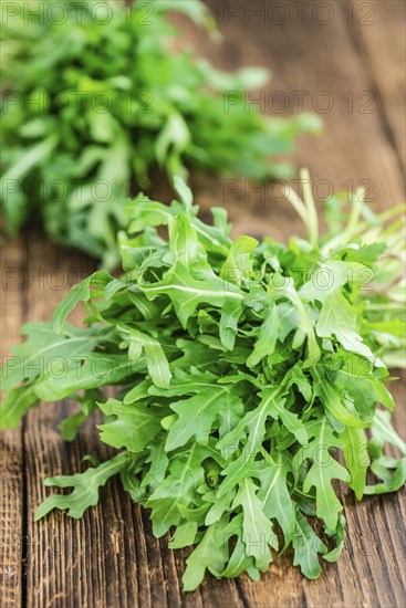 Wooden table with fresh Arugula as detailed close-up shot (selective focus)