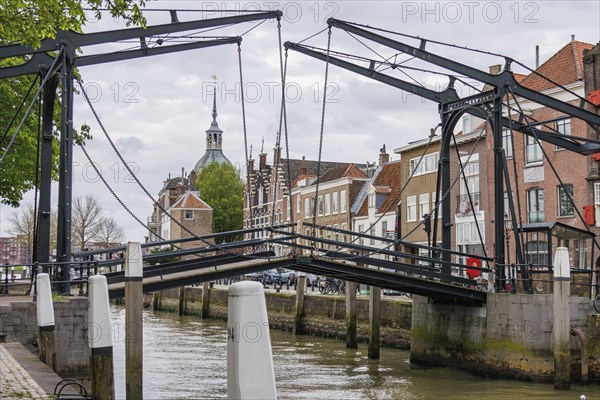View of a historic bridge over a canal, with church tower and neighbouring houses in the