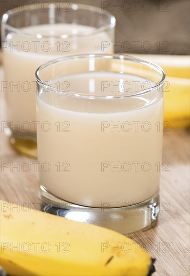 Fresh Banana Juice in a glass (detailed close-up shot) on wooden background